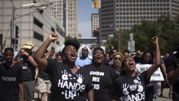 Activists raise their hands as they demand justice for the killing of Michael Brown while marching to the Thomas F. Eagleton United States Courthouse from City Hall in downtown St. Louis, Missouri