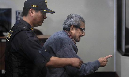 El fundador de Sendero Luminoso, Abimael Guzmán (d), es custodiado por un policía durante una audiencia en la Base Naval del Callao en Perú.