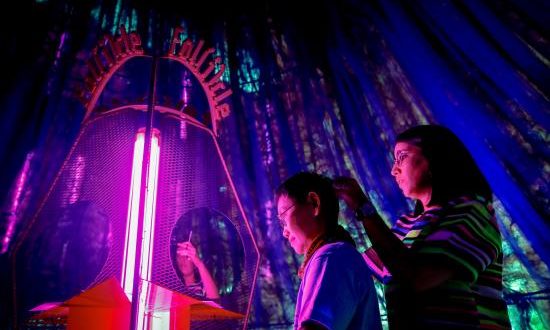 La creadora española Déborah López corta un mechón de pelo a un hombre dentro de su instalación artística hecha con pelo humano "Folículo: una cartografía tóxica de Bangkok", este martes, durante la Semana del Diseño de Bangkok. EFE