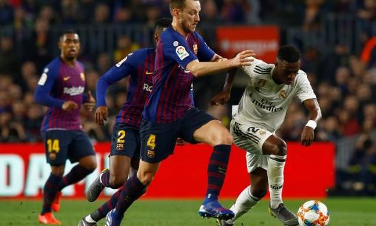 El delantero brasileño del Real Madrid Vinicius Junior (d) se escapa del croata Ivan Rakitic, del FC Barcelona, durante el partido de ida de las semifinales de la Copa del Rey que FC Barcelona y Real Madrid jugaron en el Camp Nou, en Barcelona. EFE