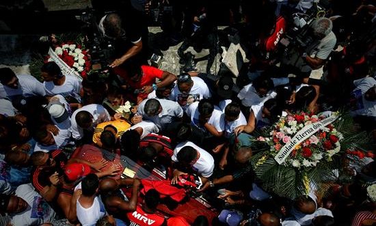 Amigos y familiares acompañan el féretro del joven arquero Christian Esmerio, una de las 10 jóvenes promesas del fútbol que perdió la vida en el incendio desatado el viernes en una de las sedes del club Flamengo, durante su sepelio este domingo en el cementerio de Iraja, en Río de Janeiro (Brasil). EFE