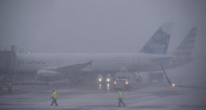 Varios trabajadores del aeropuerto asisten al despegue de un avión en Arlington, Virginia (Estados Unidos), este miércoles, durante una jornada de tormenta de nieve y bajas temperaturas. EFE