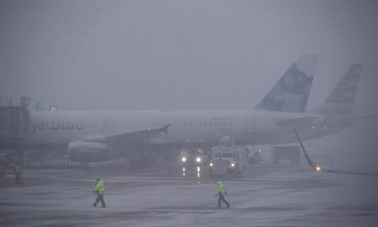 Varios trabajadores del aeropuerto asisten al despegue de un avión en Arlington, Virginia (Estados Unidos), este miércoles, durante una jornada de tormenta de nieve y bajas temperaturas. EFE