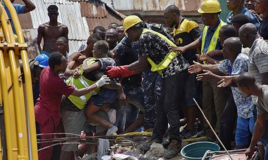Operarios rescatan a un niño entre los escombros tras derrumbarse un edificio este miércoles en Lagos, Nigeria. EFE