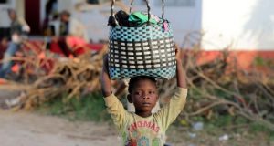 Una niña transporta ropa llegada en un barco en el río Buzi en Sofala (Mozambique), este miércoles. EFE