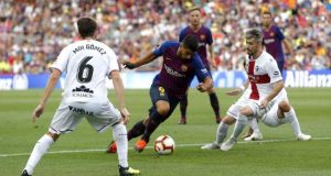 El delantero uruguayo del FC Barcelona, Luis Suárez (c), intenta escaparse de los jugadores del Huesca, el centrocampista Moi Gómez (i) y el defensa portugués Luisinho (d), durante el partido de la tercera jornada de Liga en Primera División. EFE/Archivo